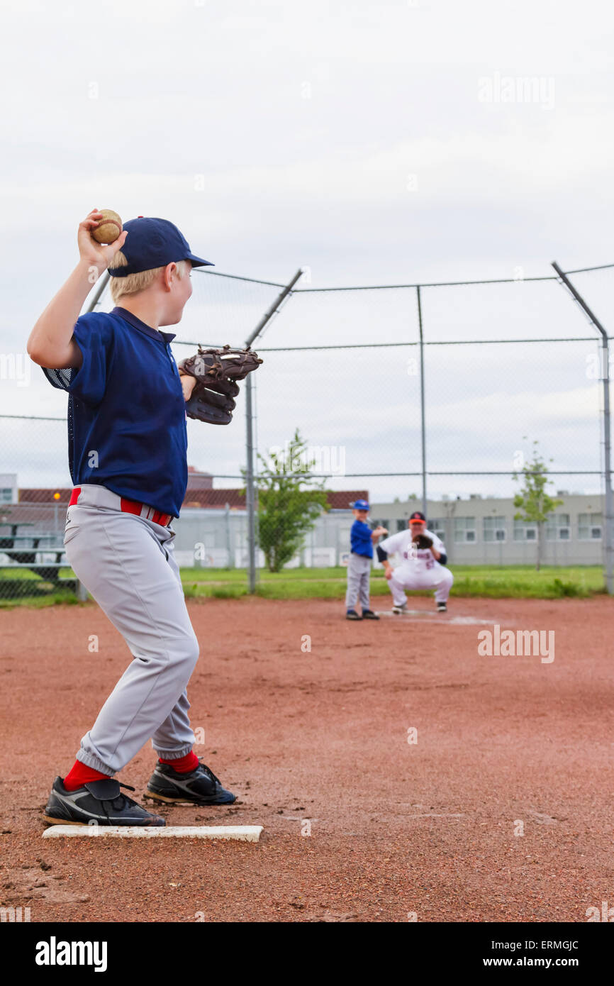 A young boy in his baseball uniform prepares to throw a pitch to his