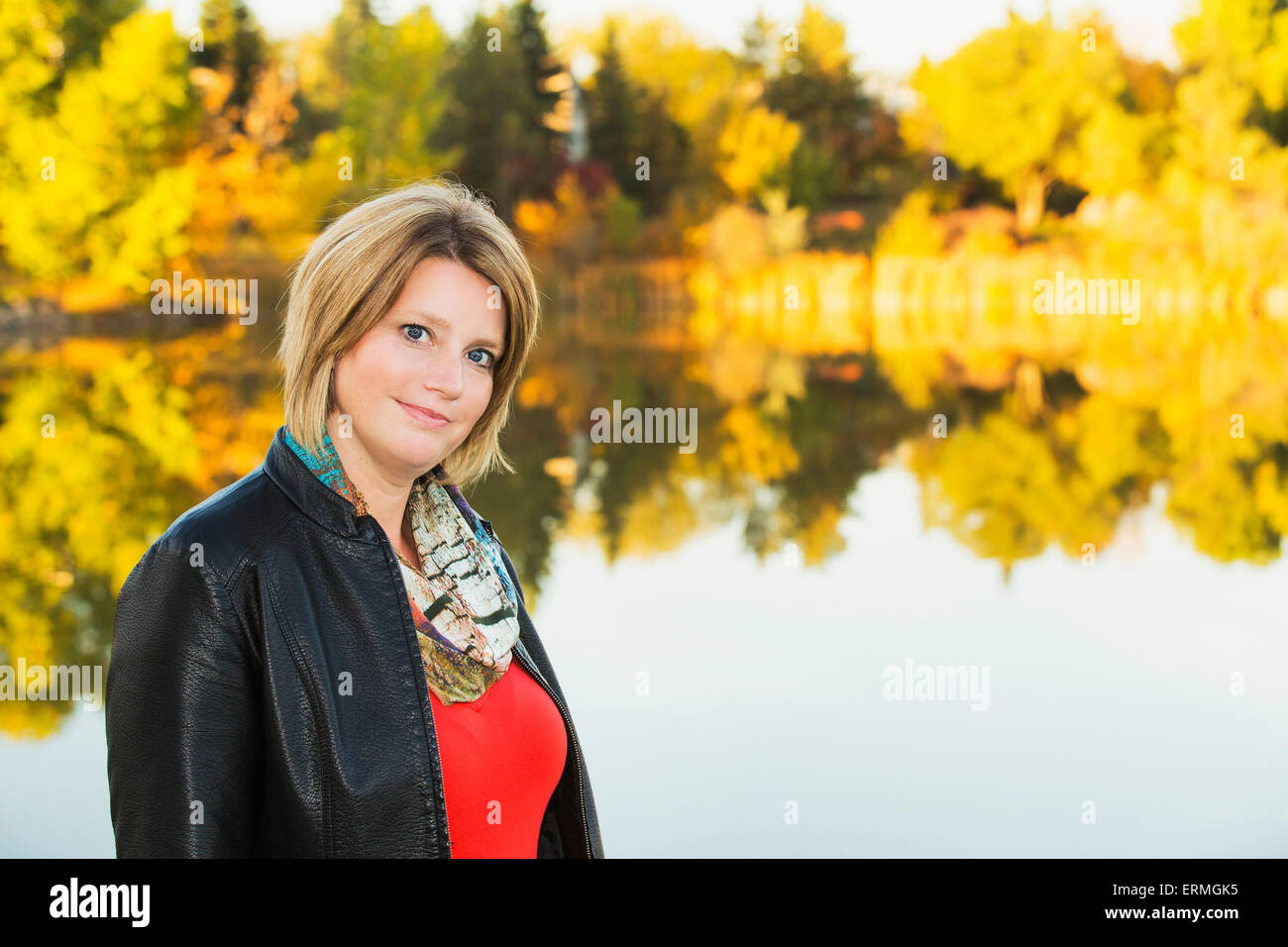 Portrait of a mature woman in a park beside a lake in autumn; Edmonton, Alberta, Canada Stock Photo