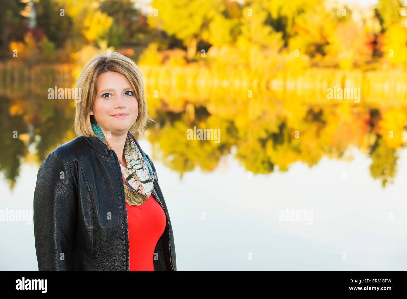 Portrait of a mature woman in a park beside a lake in autumn; Edmonton, Alberta, Canada Stock Photo