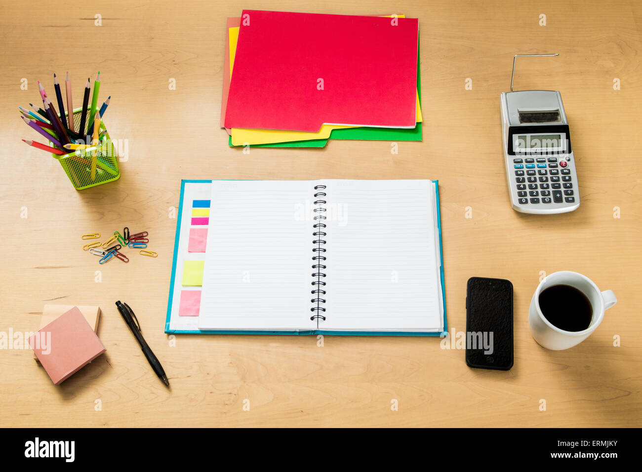 Modern creative workspace made of a flat wooden table, color pencils, a notebook,  coffee a smartphone and other objects Stock Photo