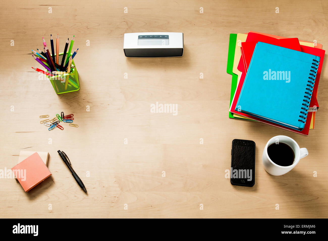 Modern creative workspace made of a flat wooden table, color pencils, a speaker, coffee a smatrphone and other objects Stock Photo