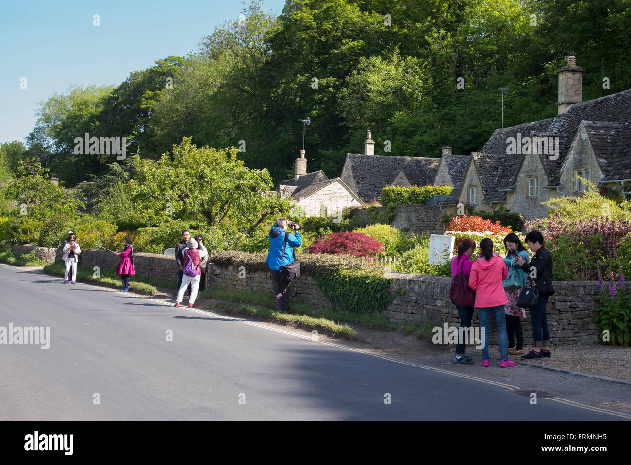 Asian tourists photographing the seventeenth century stone cottages in Bibury, Cotswolds, Gloucestershire, England Stock Photo