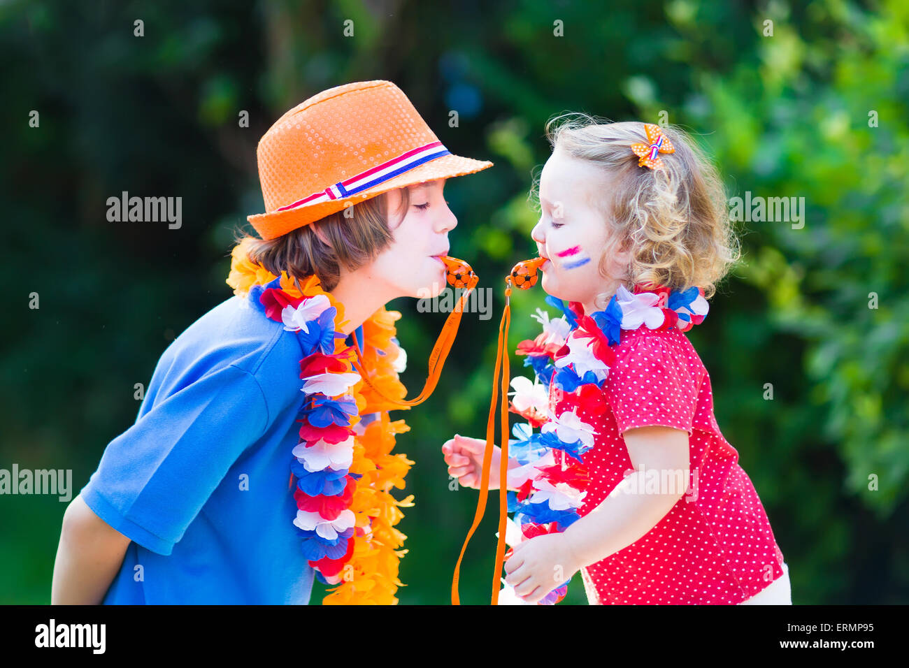 Two Dutch children, fans and supporters of Dutch football team, celebration championship  victory playing with whistles and flag Stock Photo
