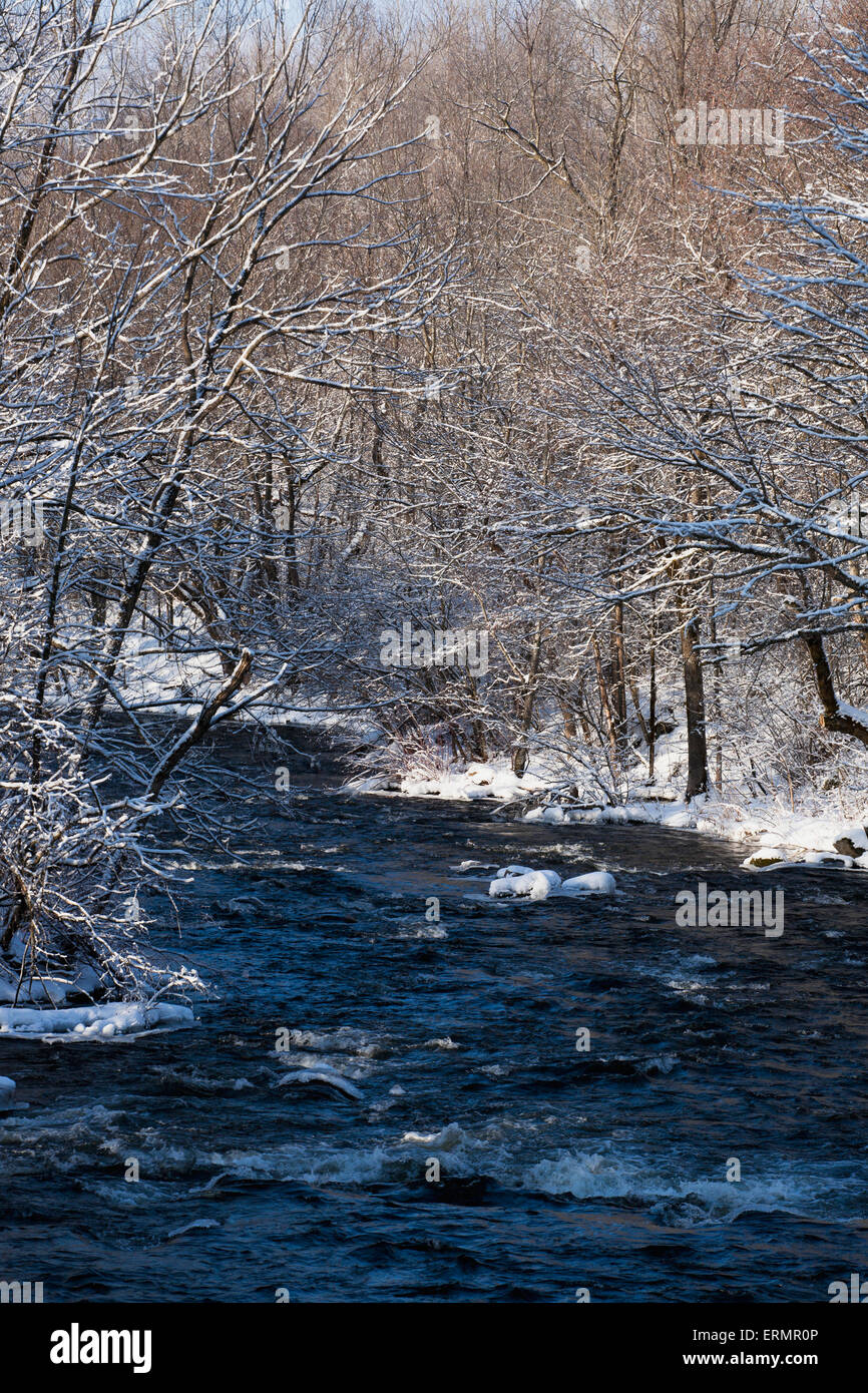 Water flowing in a river with snow covered shoreline; Fulford, Quebec