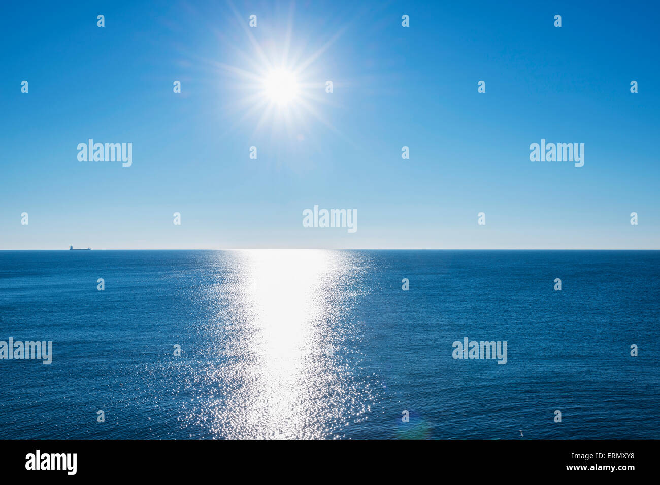 Tranquil ocean water reflecting sunlight with sun in the blue sky ...