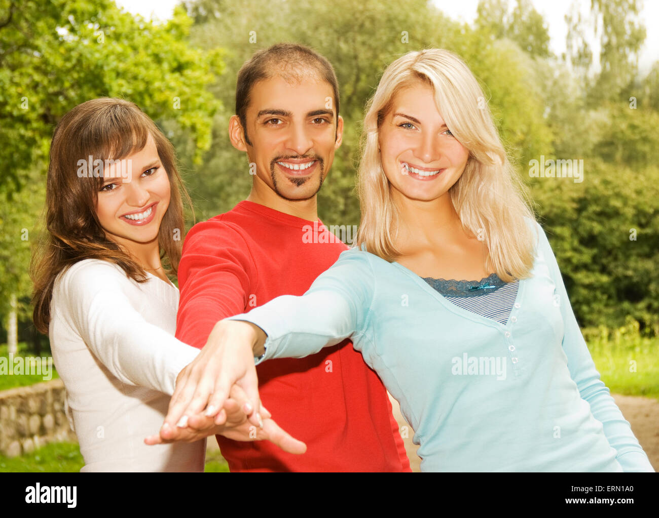 Group of young people put hands on top of each other Stock Photo
