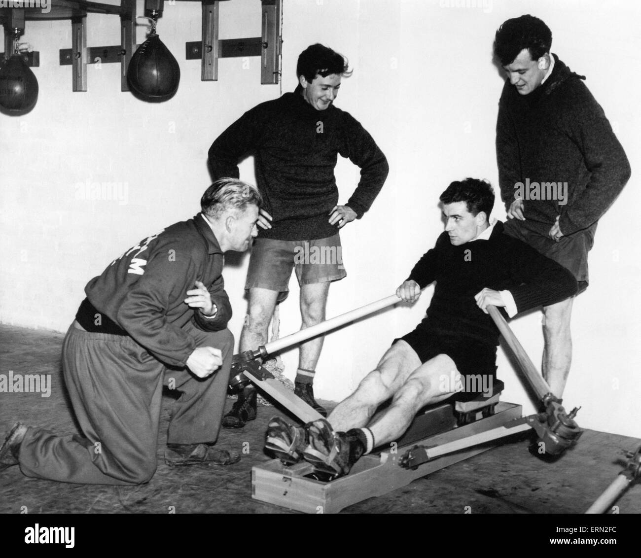Birmingham City footballer Eddie Brown takes the strain on the rowing machine watched by coach Ray Shaw and teammates Jeff Hall and Trevorr Smith during training.  27th October 1956. Stock Photo