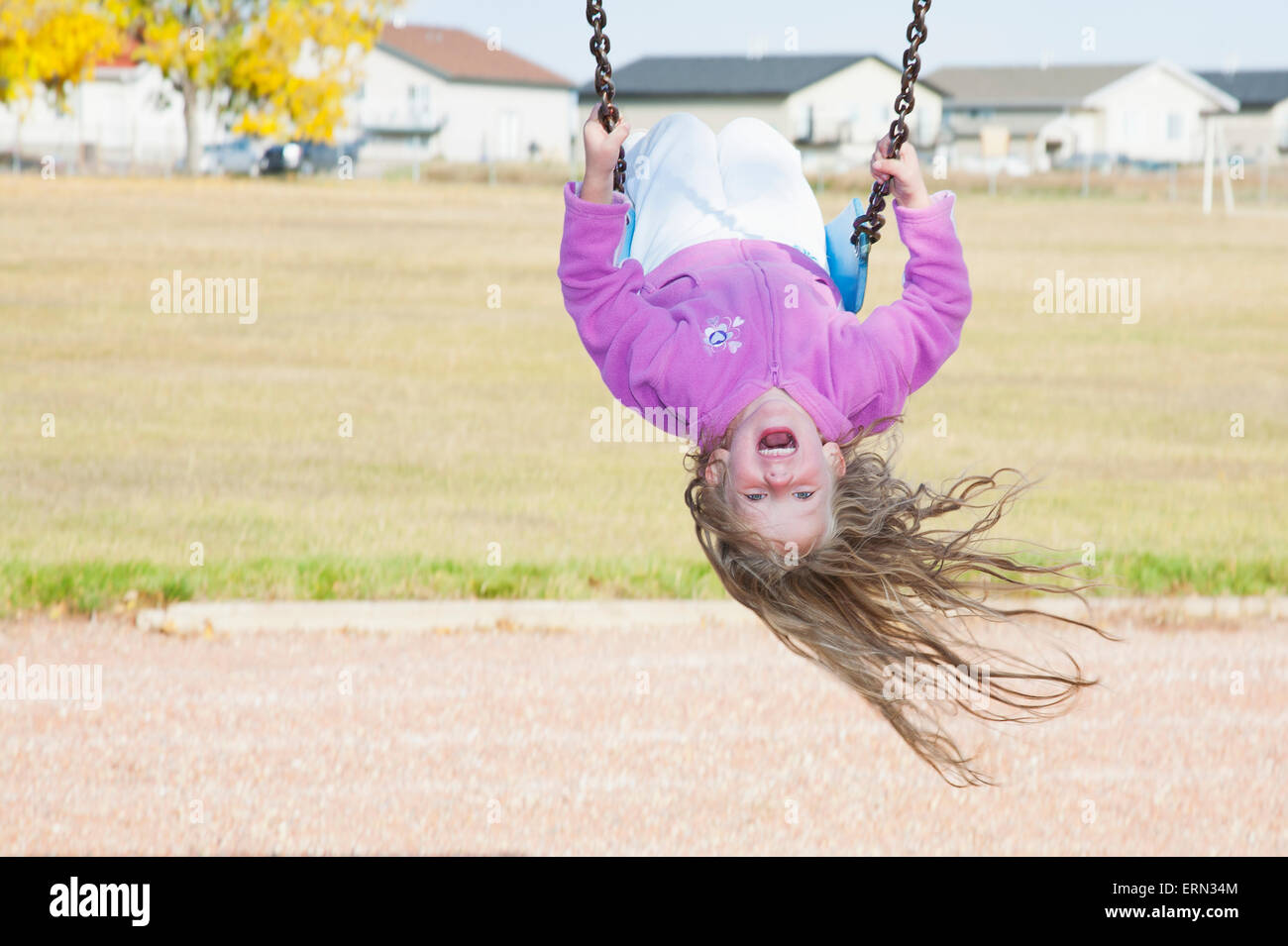 Young girl on swing in a playground in residential community on a cool,  windy fall day; Three Hills, Alberta, Canada Stock Photo - Alamy
