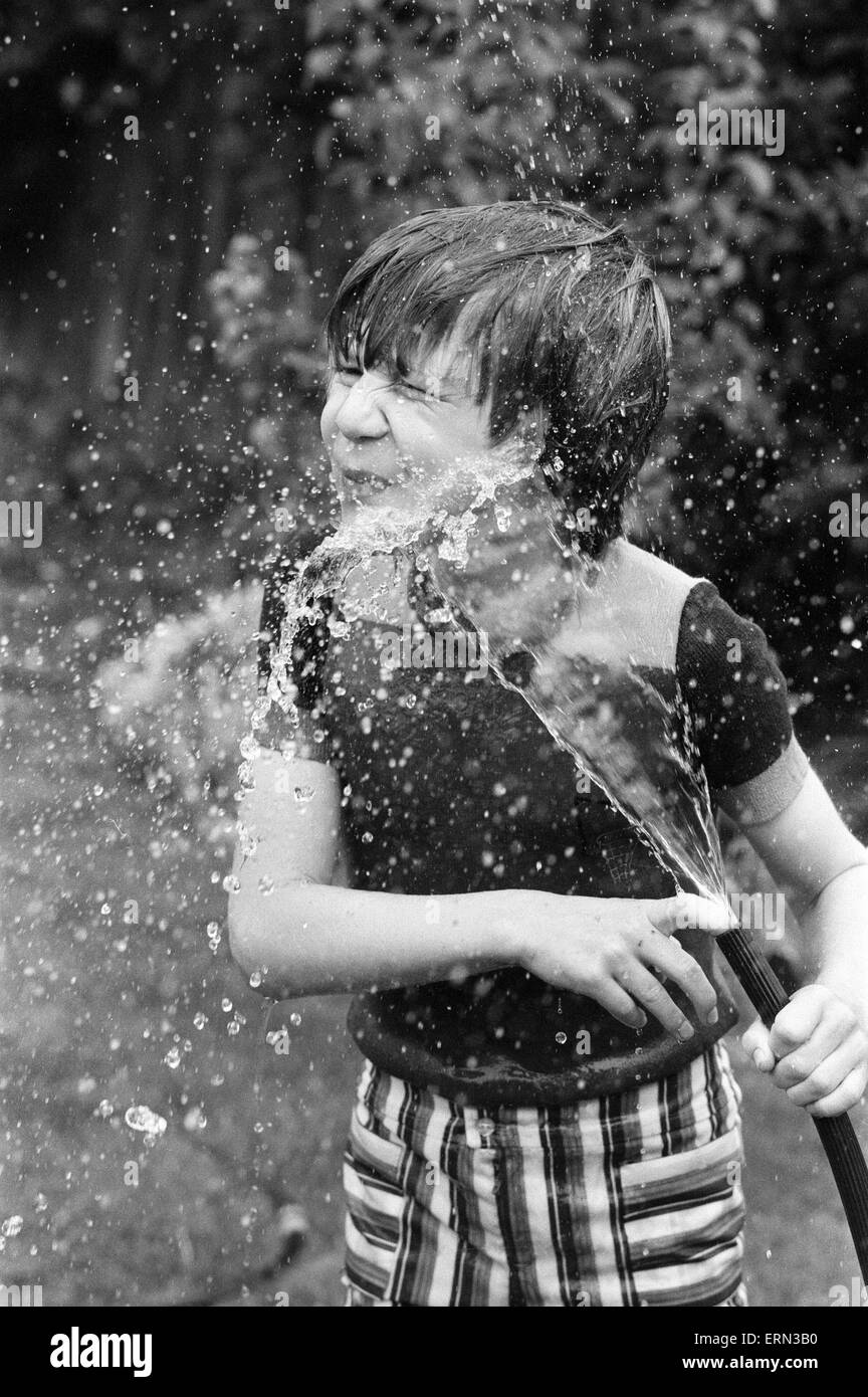 Summer Holiday fun for children playing in the sunshine. Michael Bishop of Beresford Road, Cheam, Surrey plays with the water hose in the back garden. 27th July 1977. Stock Photo
