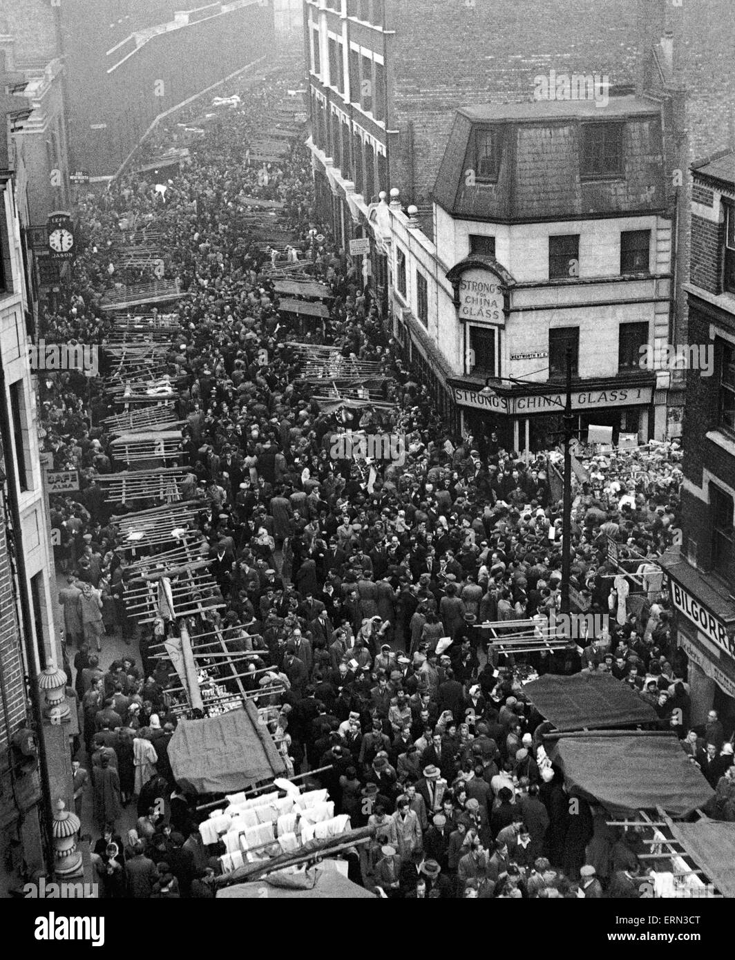 Crowds besieged Petticoat lane to buy their Christmas presents and as usual developed into a milling throng. Every conceivable item was on sale including baked chestnuts, ice cream, sleeping dolls and rat traps. A band of blind musicians were playing Chri Stock Photo