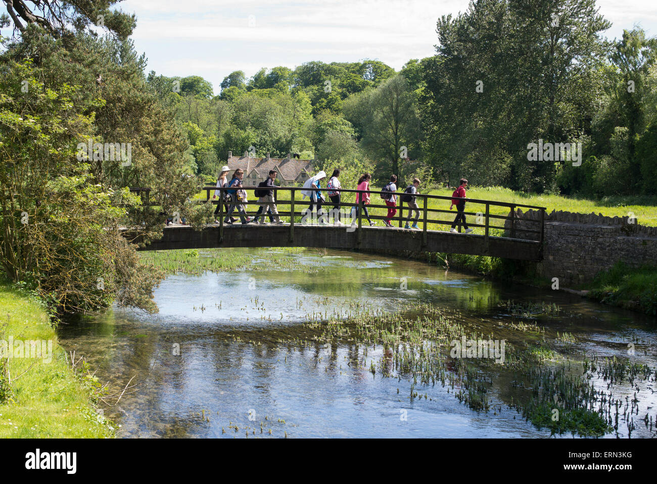 Tourists on a bridge walking over the river coln in Bibury, Cotswolds, Gloucestershire, England Stock Photo