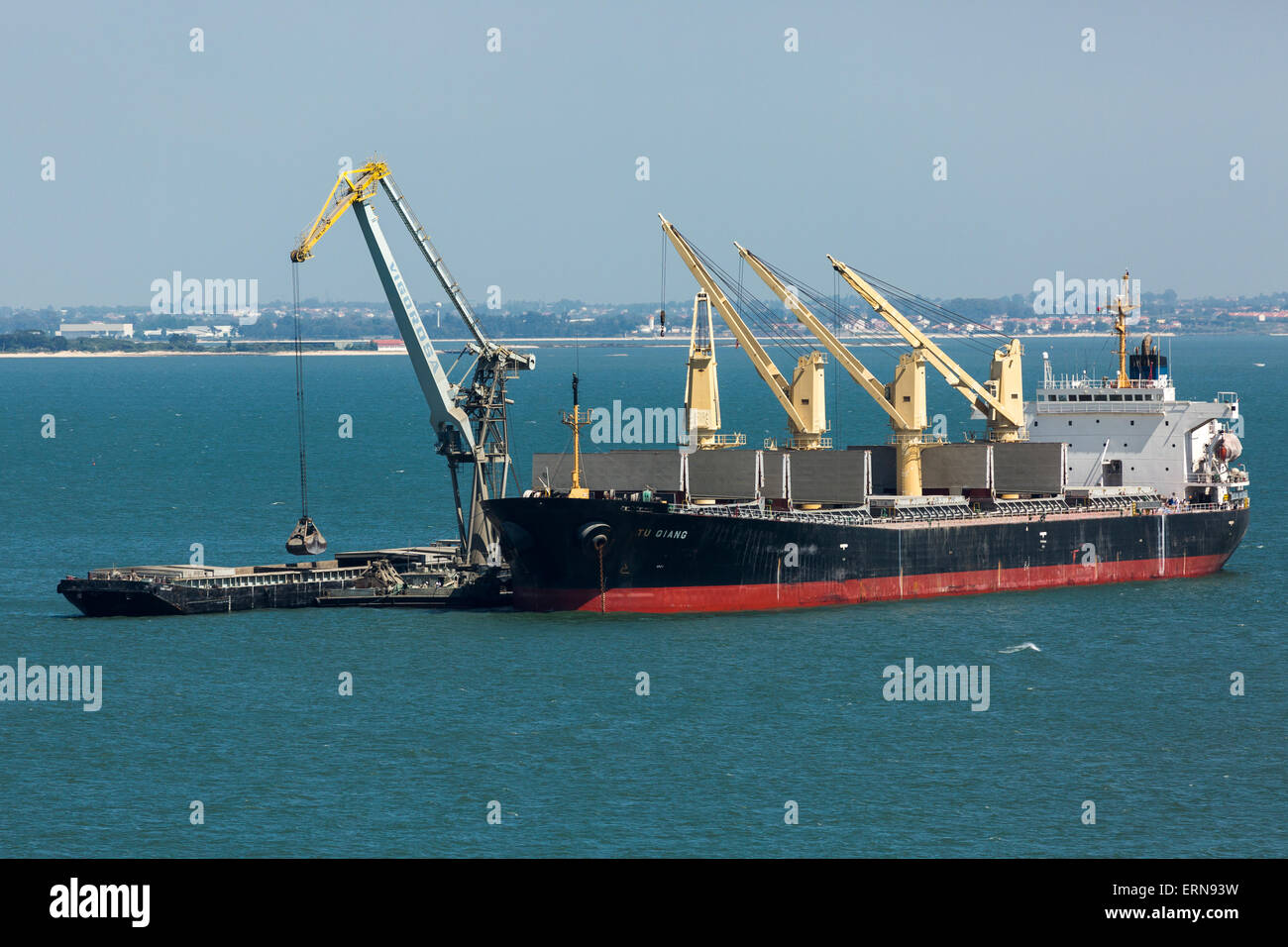 busy Lisbon harbor. bulk carrier ship discharging cargo into barges