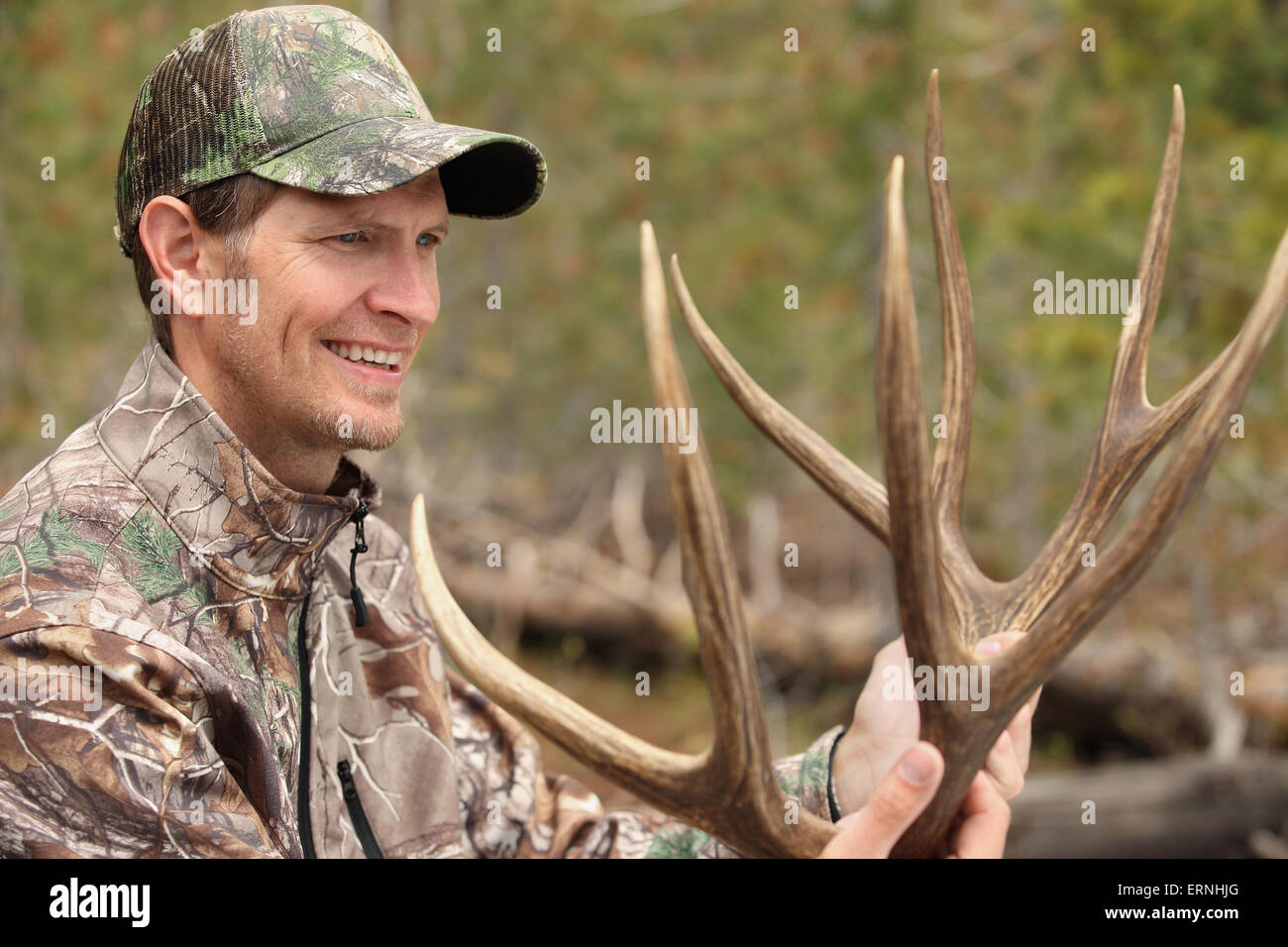 happy hunter holding harvested deer antlers Stock Photo