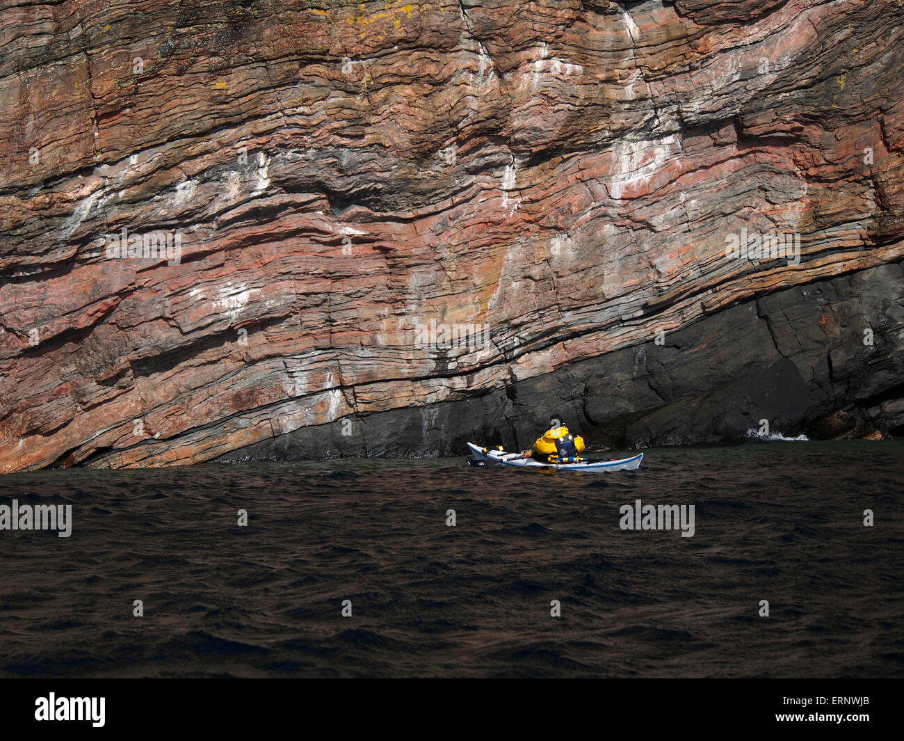 sea kayaking past cliffs of gneiss on east coast of Raasay, Scotland