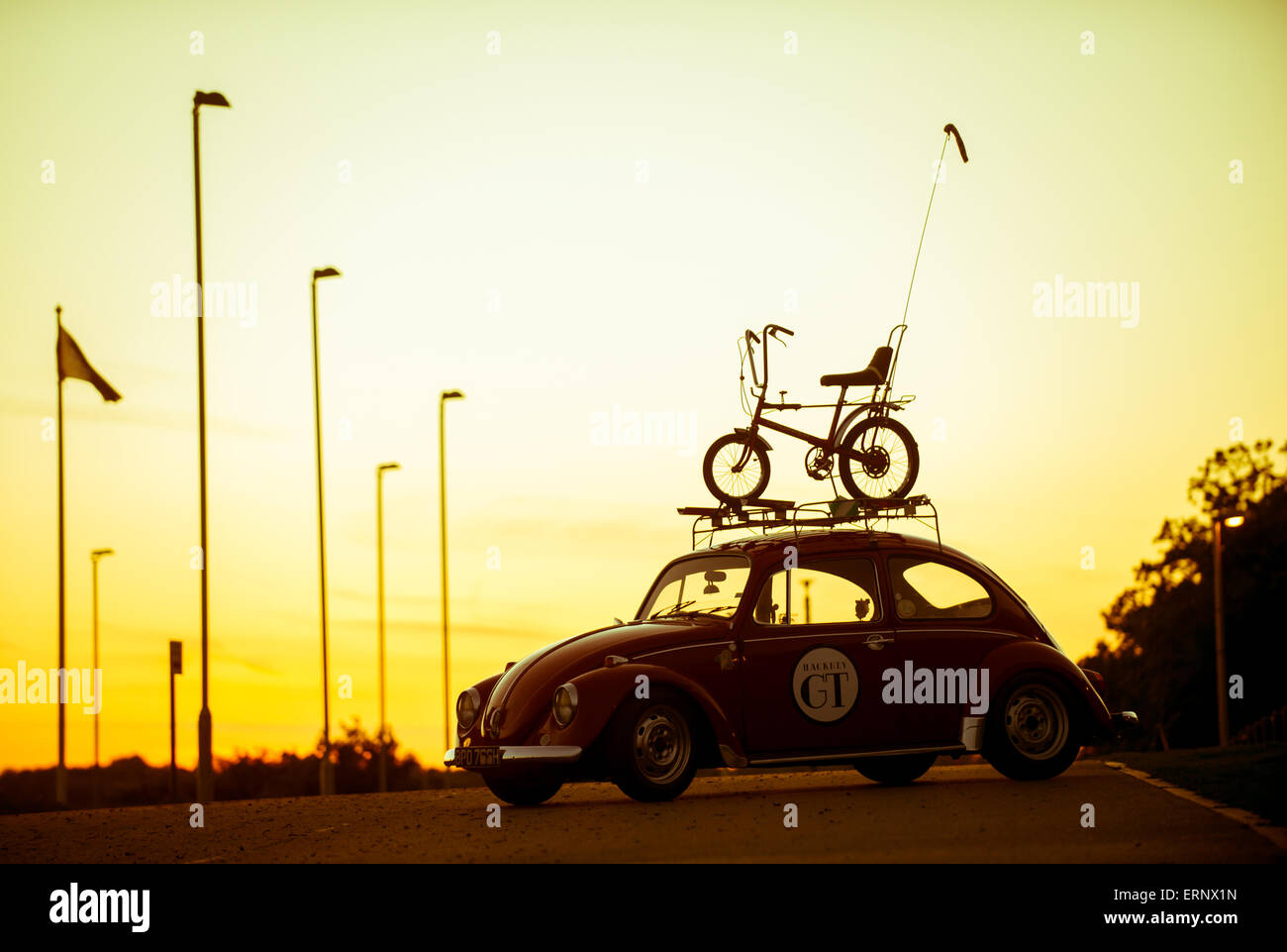 Iconic 1970s silhouettes of a Raleigh Chopper and Volkswagen Beetle against a sunset backdrop. Stock Photo