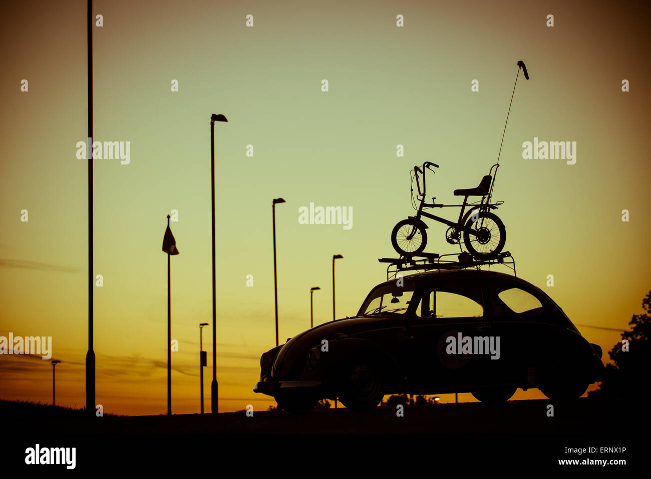 Iconic 1970s silhouettes of a Raleigh Chopper and Volkswagen Beetle against a sunset backdrop. Stock Photo