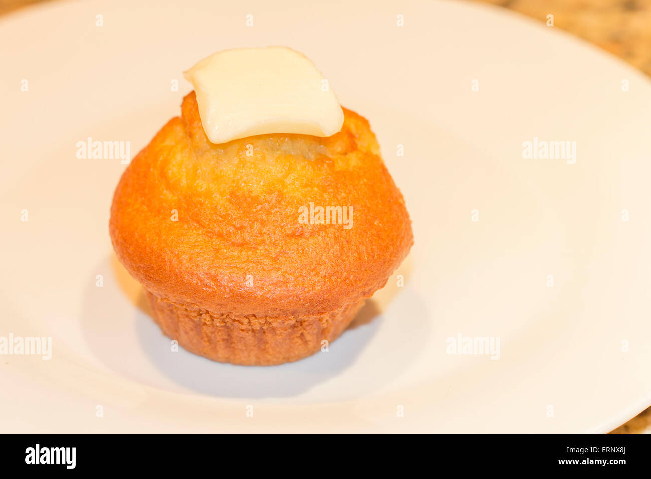 Single fresh corn muffin with slice of butter Stock Photo