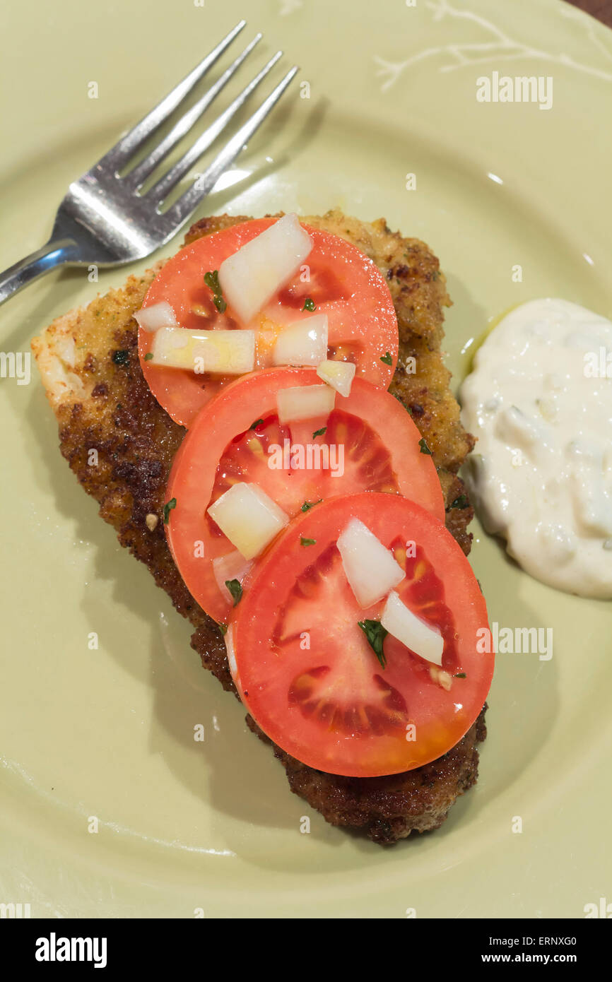 Breaded cod fillet with tomato and onion with tartar sauce Stock Photo