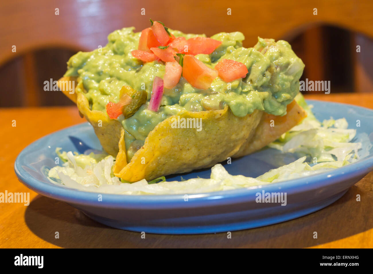 Mexican Guacamole dip with diced tomatoes in a crunchy tortilla bowl Stock Photo