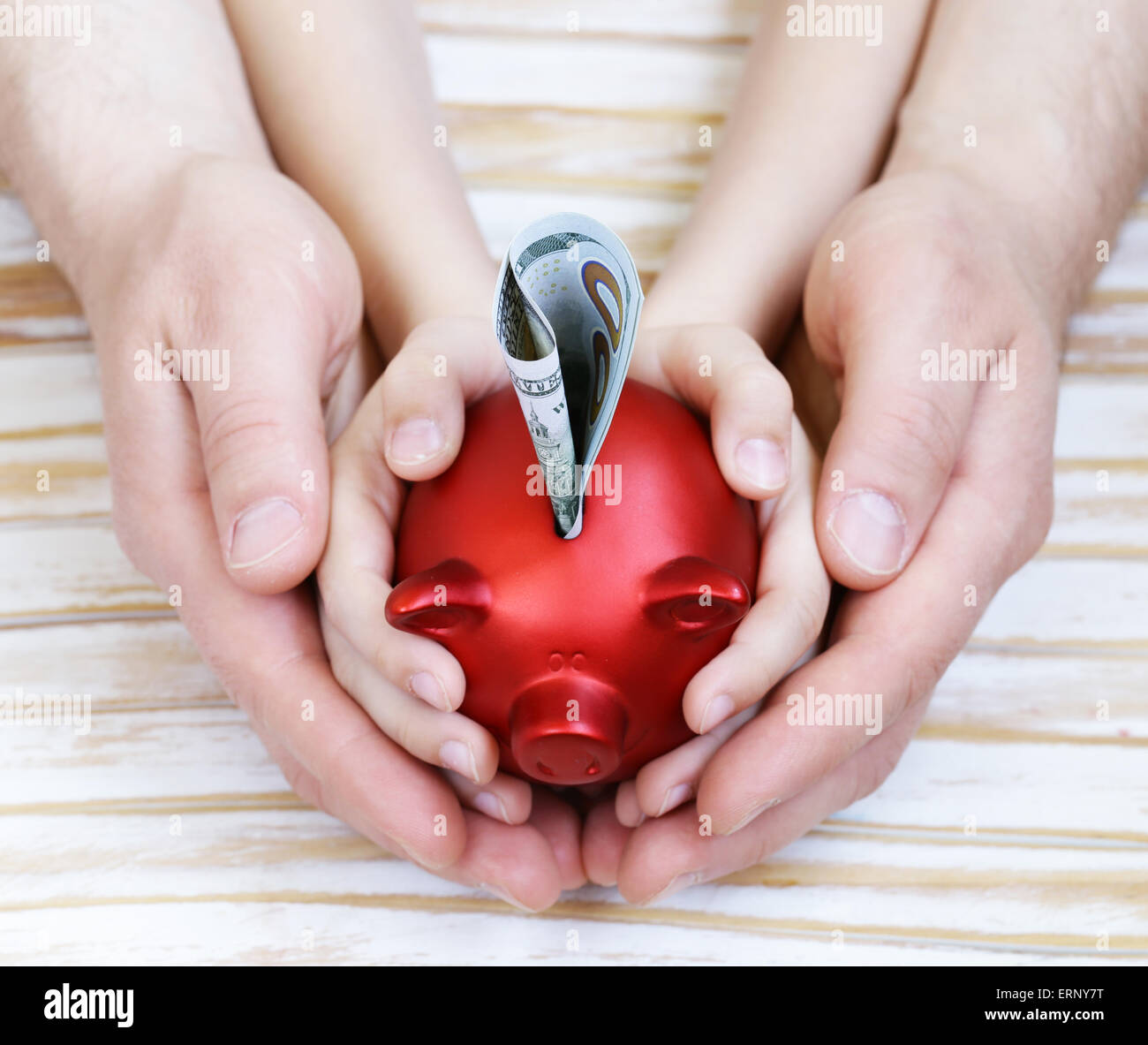 close up of father and son hands holding red piggy bank Stock Photo - Alamy