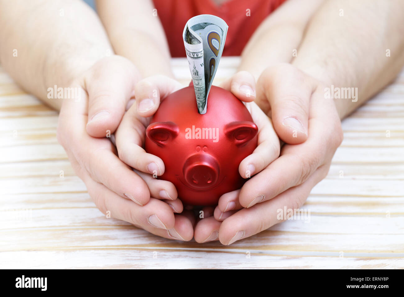 close up of father and son hands holding red piggy bank Stock Photo - Alamy