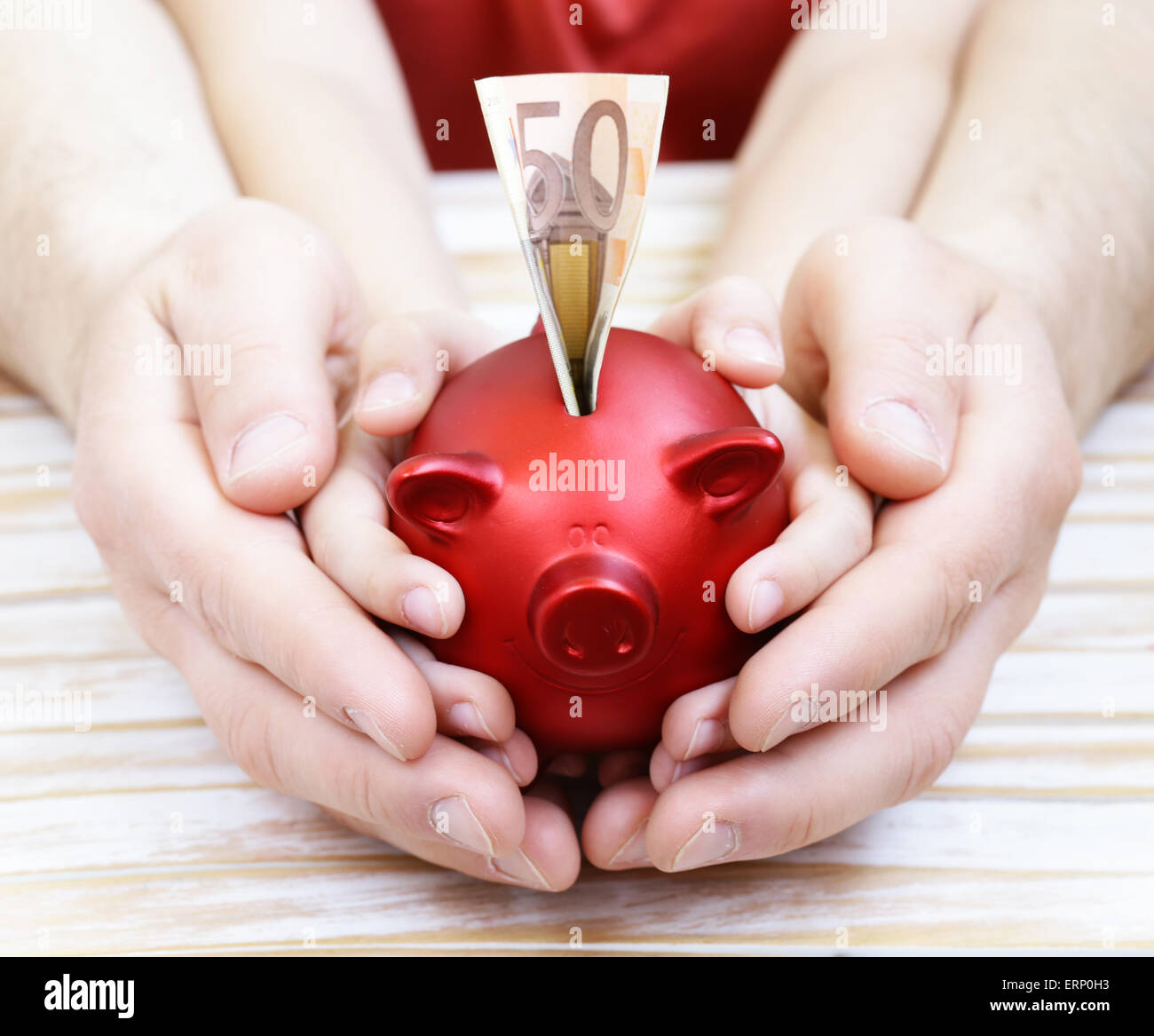 close up of father and son hands holding red piggy bank Stock Photo - Alamy