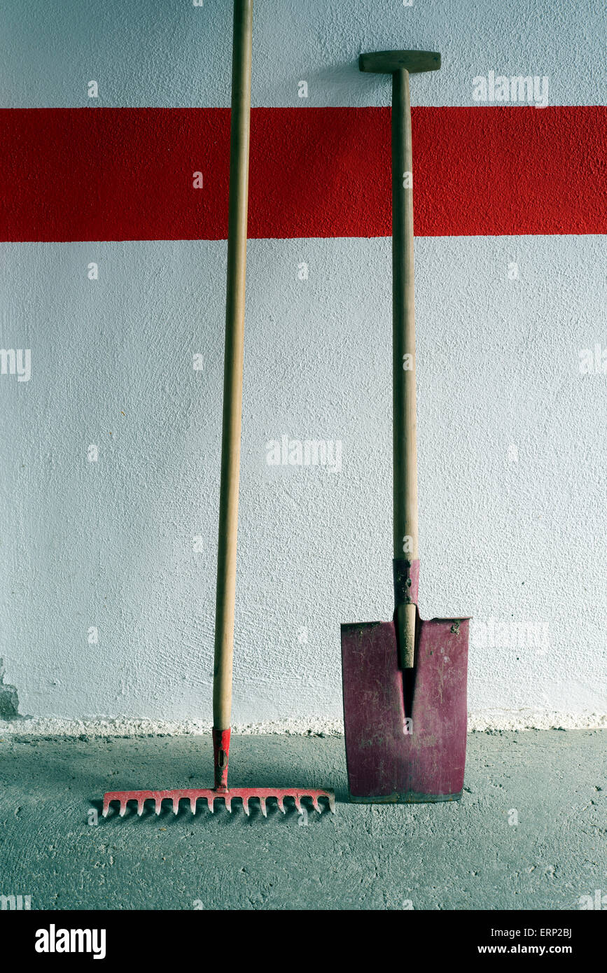 shovel and rake red on white wall with red stripe Stock Photo