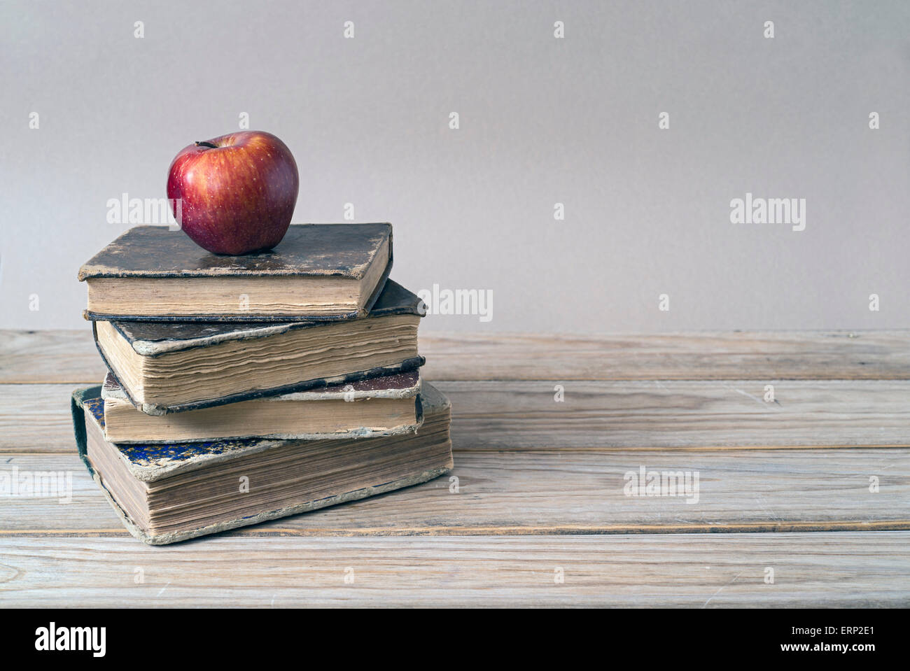 Stack of books and red apple on wooden table. Copy space Stock Photo