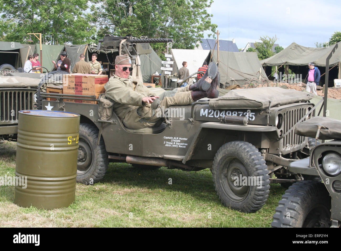 Carentan, Normandy, France. 6 June 2015. Reenactment groups go to great lengths to recreate Camp Arizona on the original site near Carentan in Normandy as part of the D-Day festival 2015. Here a man dressed as a member of the US army relaxes during the D-Day anniversary in an original US army jeep. This year's D-Day Festival commemorates the 70th year of the end of WWII in 1945. Credit:  Daniel and Flossie White/Alamy Live News Stock Photo