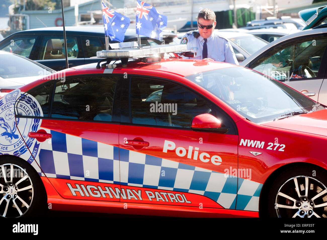 New south wales policeman standing by his highway patrol police car at palm beach Sydney,adorned with two australian flags Stock Photo