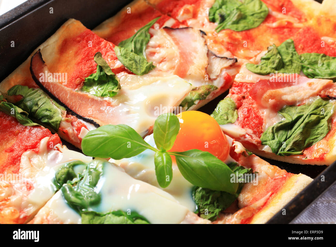 Pizza with prosciutto, spinach leaves and sunny side up egg on top