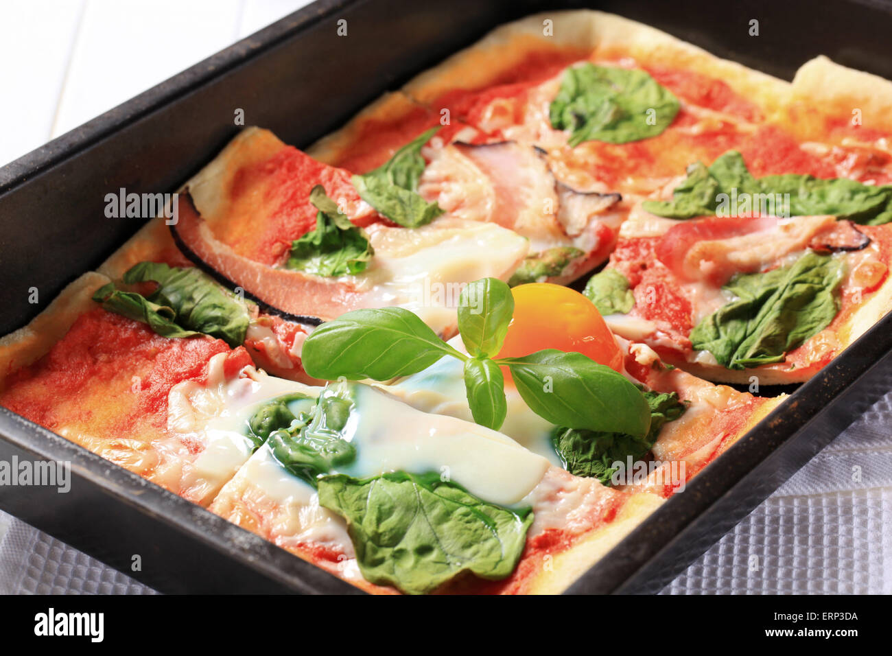 Pizza with prosciutto, spinach leaves and sunny side up egg on top