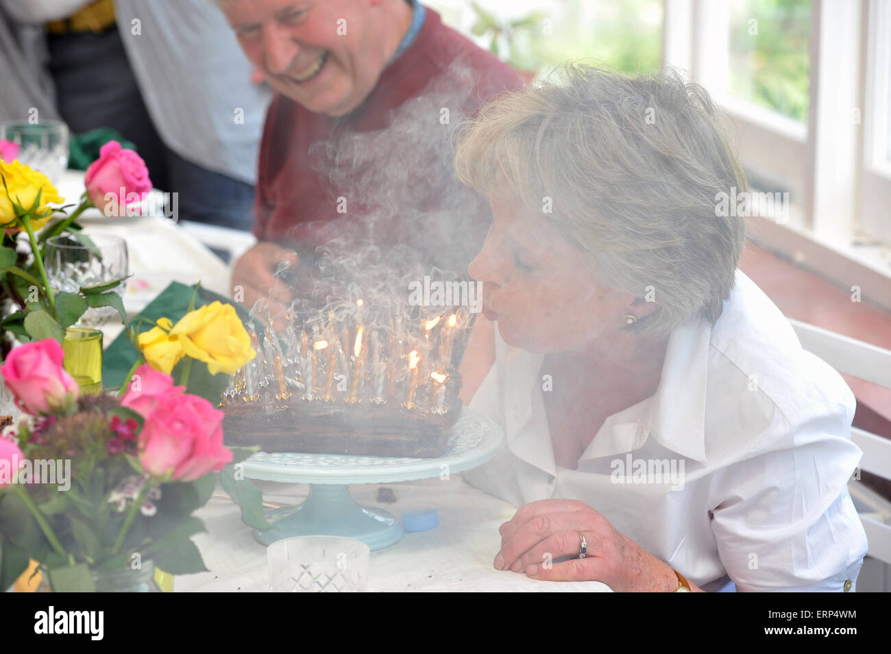 A very happy birthday grandmother blows out her candles Stock Photo
