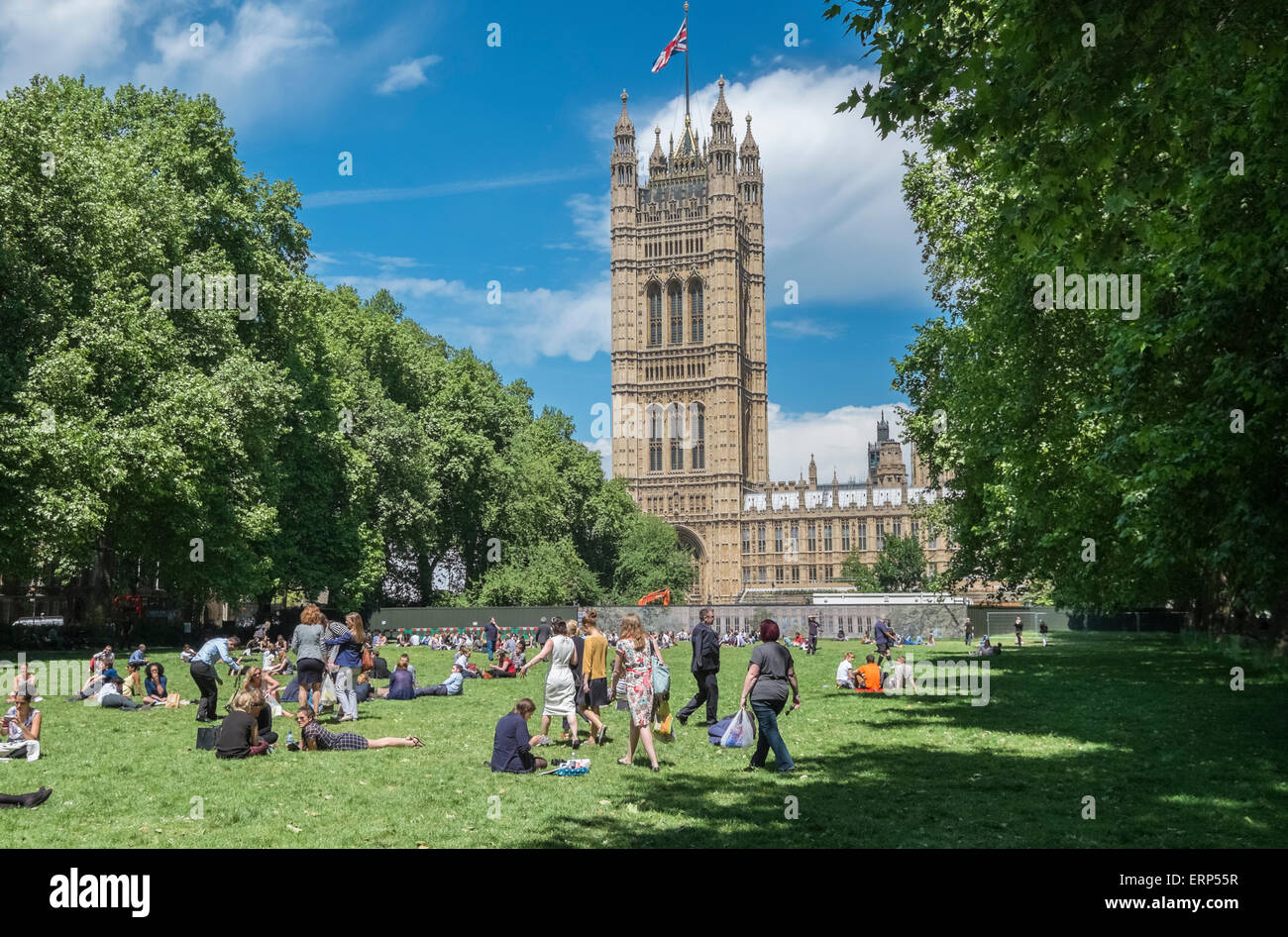 People relaxing in sunshine on a sunny summers day near Houses of Parliament, Victoria Tower Gardens, Westminster, London UK Stock Photo