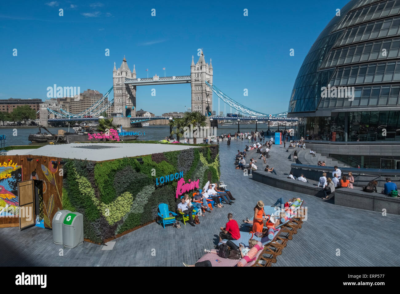 People relaxing in sunshine at London Riveria, with Tower Bridge and