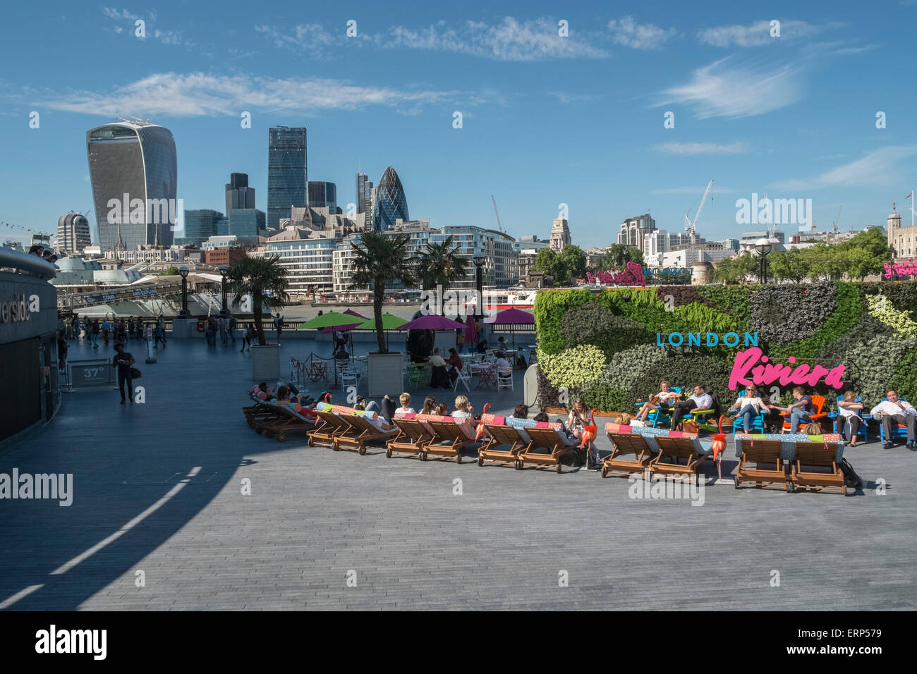 People relaxing in sunshine at London Riviera, with modern skyline architecture in background, Southbank, Southwark, UK Stock Photo