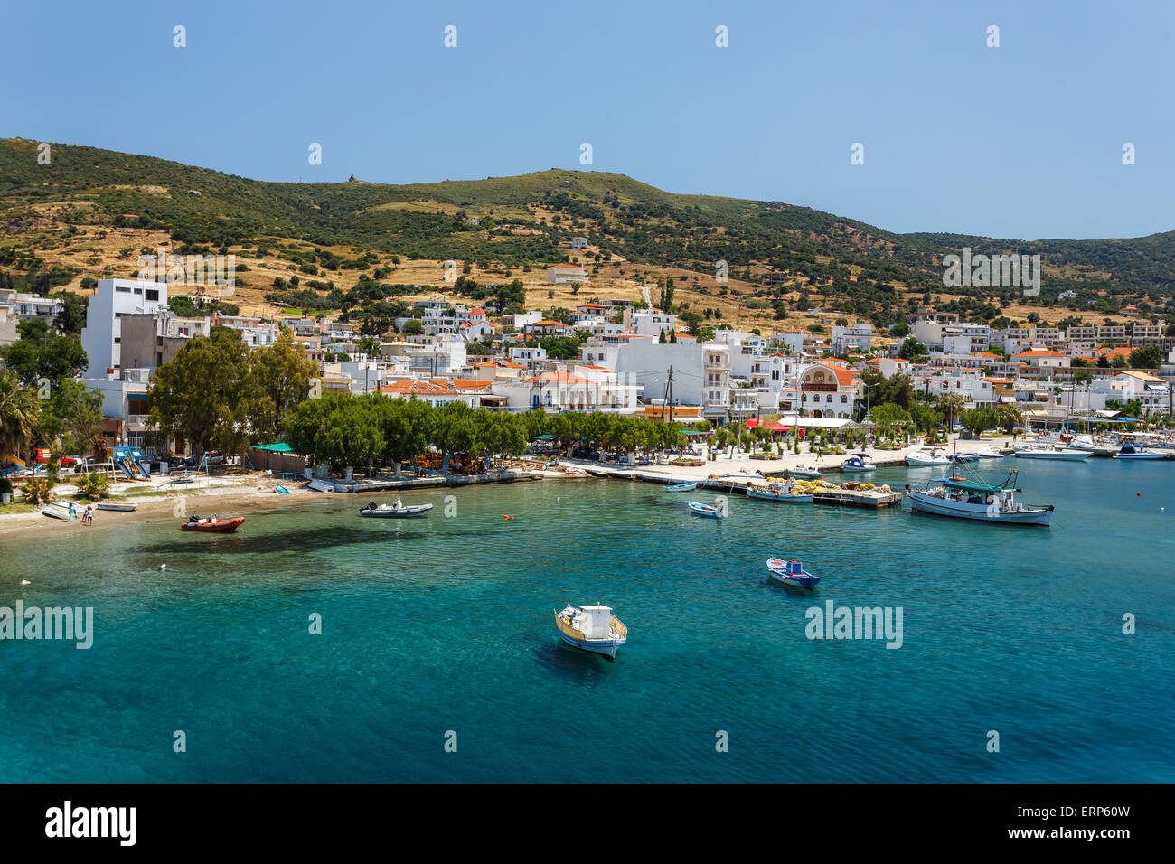 Marmari port with anchored fish boats and white houses against a blue sky and blue waters in Evia, Greece Stock Photo