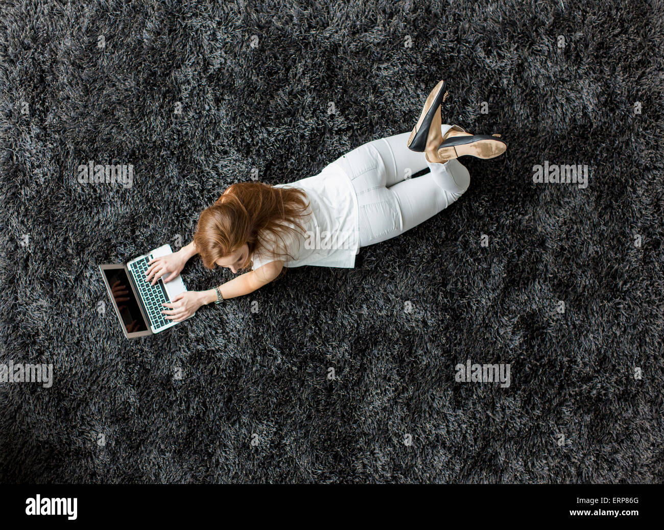Young woman laying on the carpet Stock Photo - Alamy