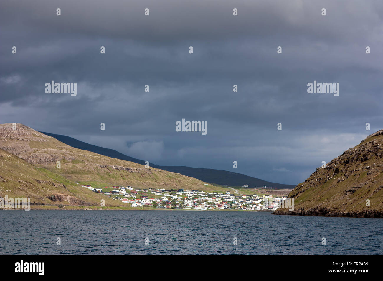 Faroe Islands, village of Sorvagur surrounded by green mountains under a dramatic sky Stock Photo