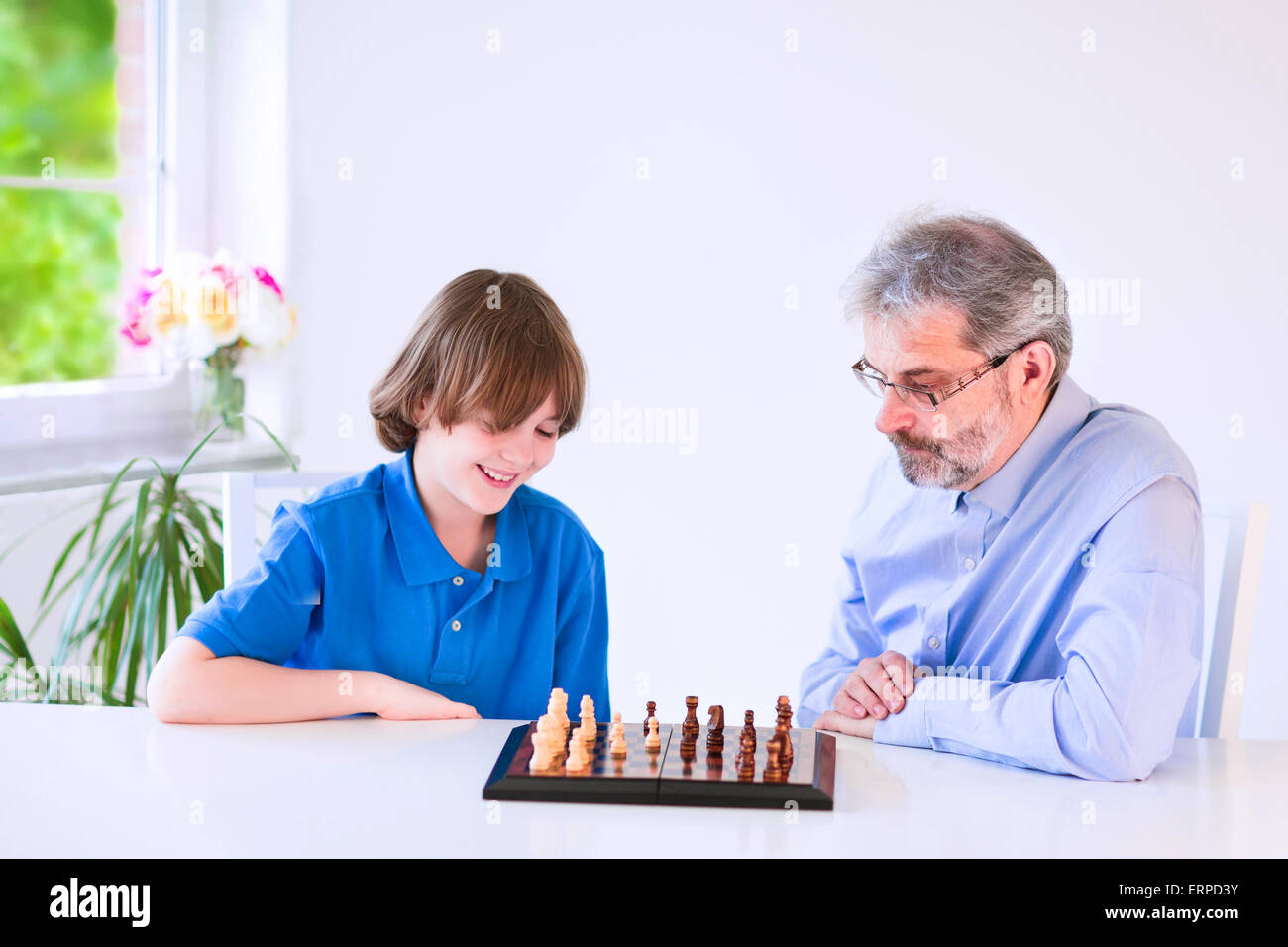 Дед с внуком играют в шашки. Дедушка и внук играют в шахматы. Дедушка играет в шашки. Ребенок играет в шахматы с дедом. Играют в шахматы дед учит внука.