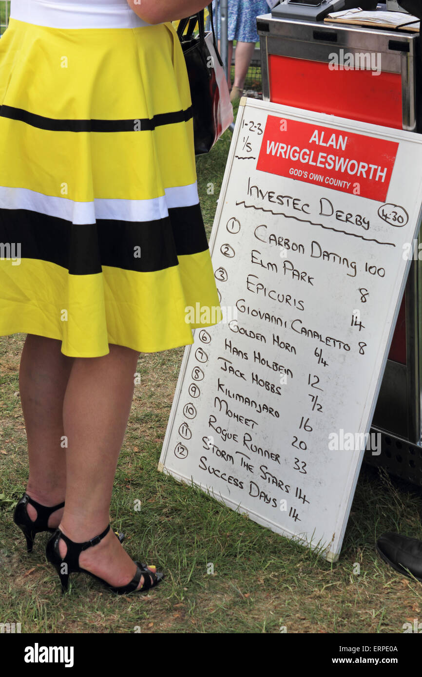 Epsom Downs Surrey UK. 6th June, 2015. Lady in yellow dress places a bet at bookmakers displaying odds for the Investec Derby. Stock Photo