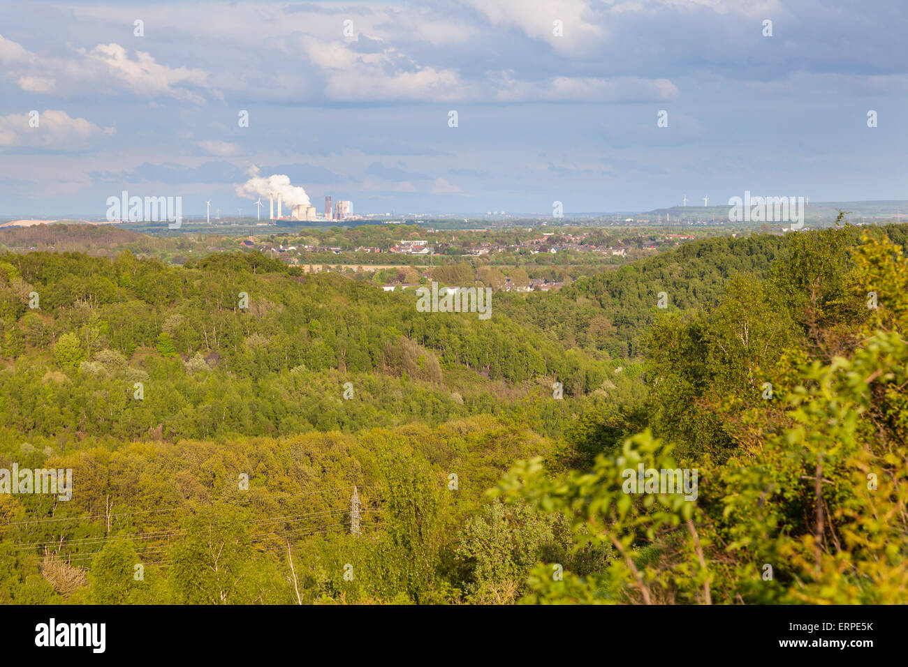 View from a slag heap over green forest in west Germany near Aachen to a distant coal-fired power station. Stock Photo