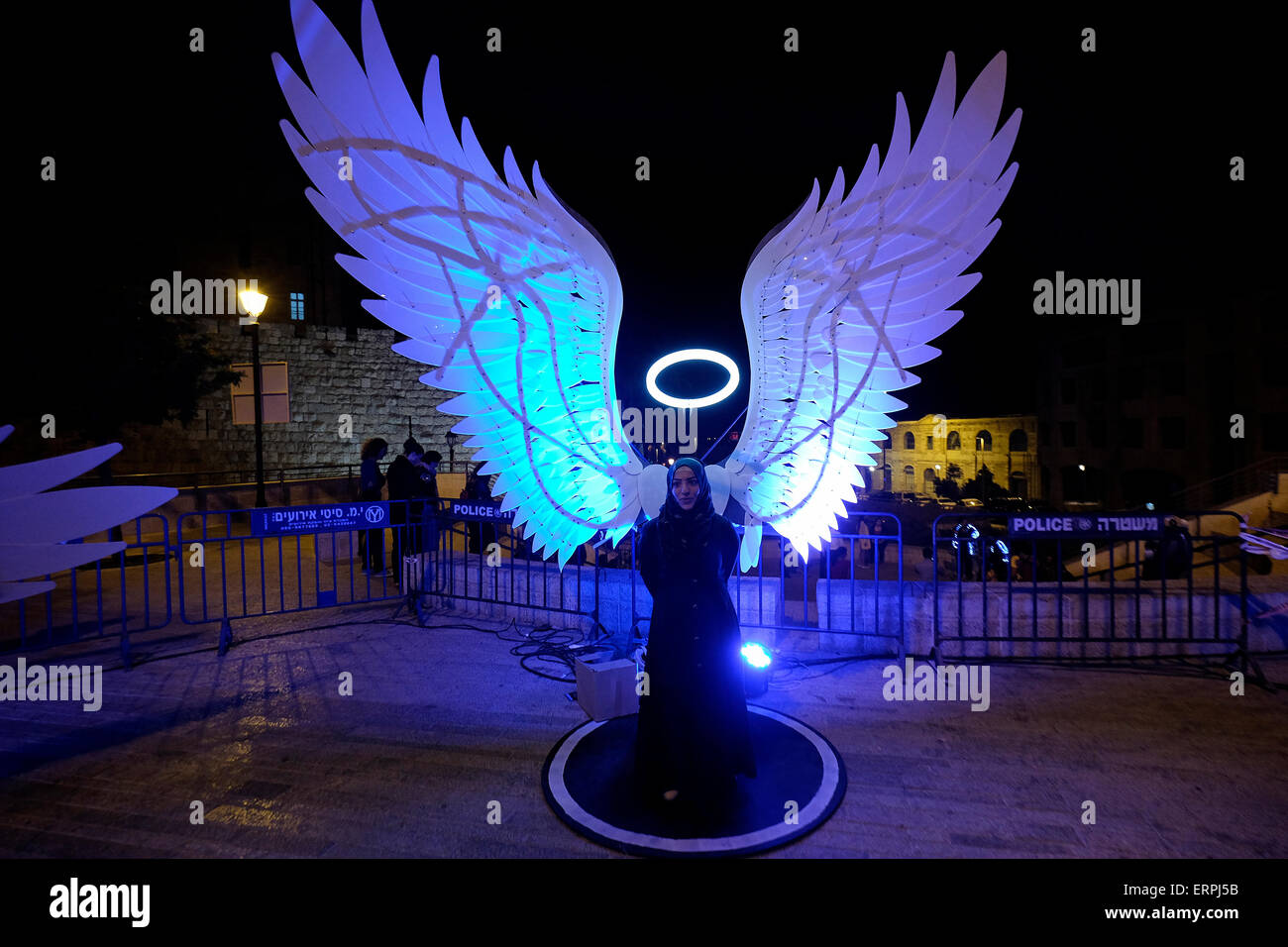 Jerusalem - ISRAEL 06 June 2015: A young Muslim woman posing with an illuminated figure depicting an angel in the old city during the Jerusalem Festival of Lights in Israel on 06 June 2015. The festival is held annually around Jerusalem's old city with special effects illuminating historical sites. Stock Photo
