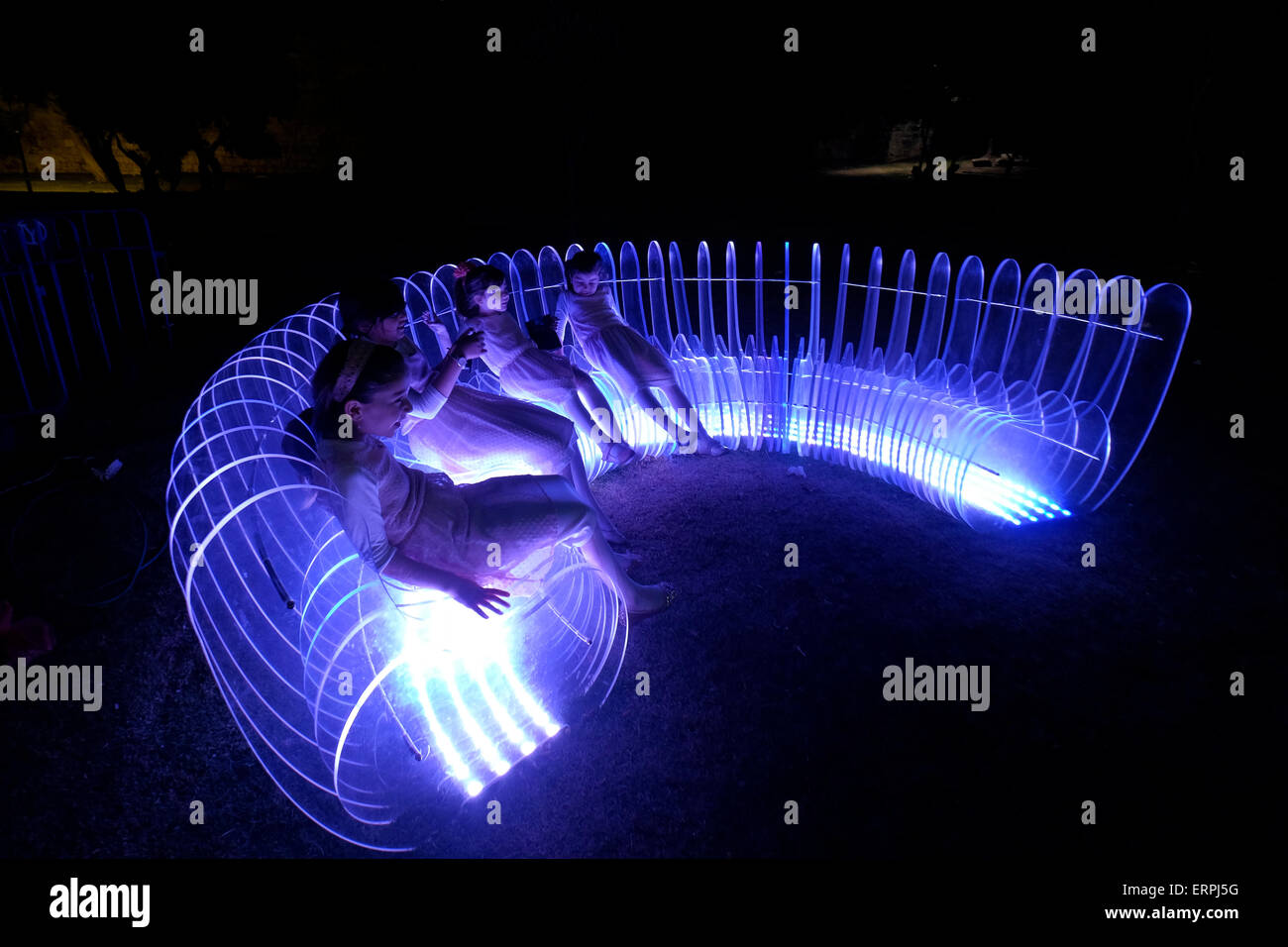 Jerusalem - ISRAEL 06 June 2015: Young Israeli girls sitting in a light art installation in the old city during the Jerusalem Festival of Lights in Israel on 06 June 2015. The festival is held annually around Jerusalem's old city with special effects illuminating historical sites. Stock Photo