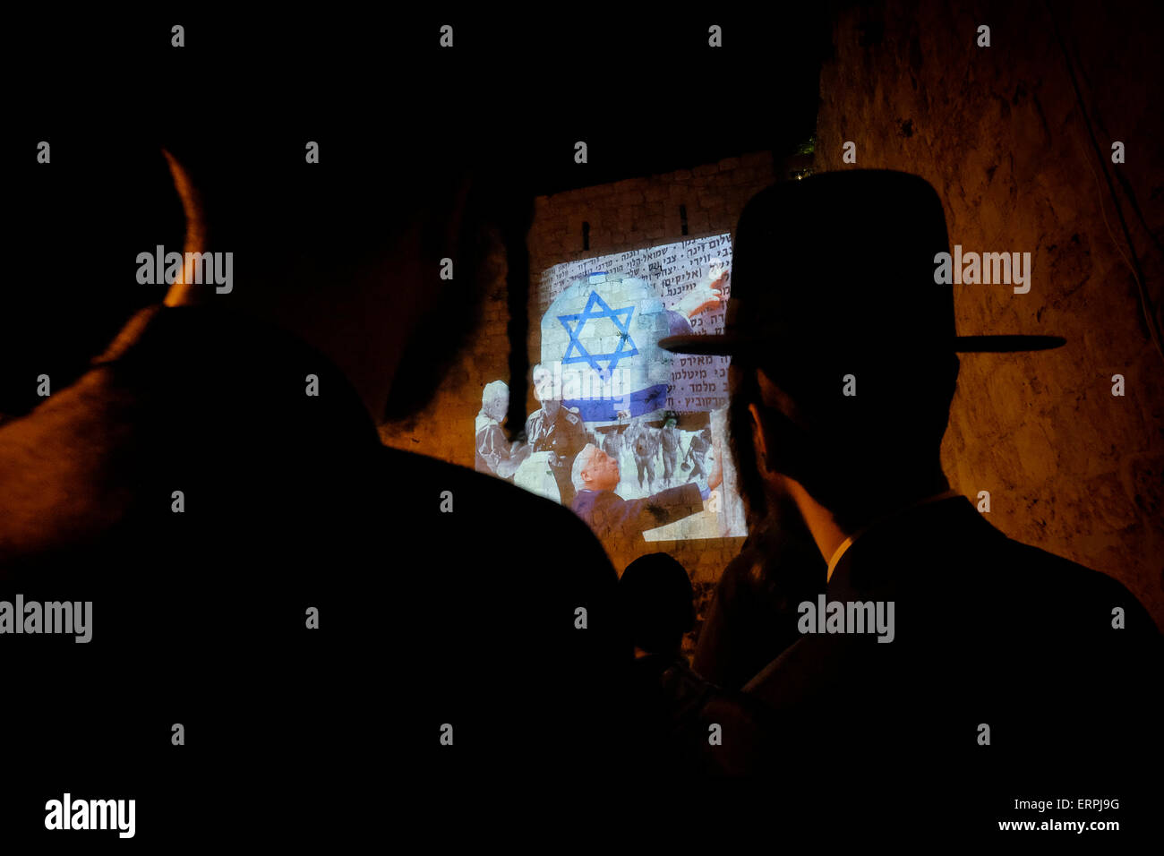 Jerusalem - ISRAEL 06 June 2015: Ultra Orthodox Jews watching a light and sound projection over ancient wall depicting the 11th Israeli Prime Minister Ariel Sharon praying in the Western Wall in the old city during The Jerusalem Festival of Lights in Israel on 06 June 2015. The festival is held annually around Jerusalem's old city with special effects illuminating historical sites. Stock Photo