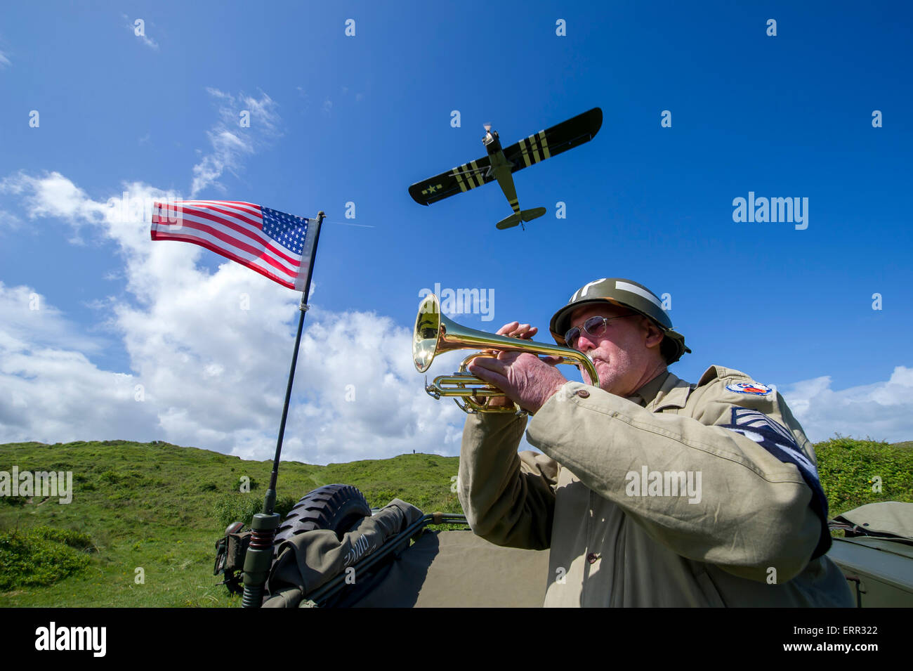 Braunton Burrows, Devon. 6th June, 2015.  Living History re-enactors take part in a D-Day commerative service marking 71 years since the D-Day landings. Pictured at Braunton Burrows, Devon where American troops trained for the invasion of Europe on June 6, 1944. Pictured is Living History bugler David Bunney playing the last post tribute as historic planes fly past.   image copyright guy harrop info@guyharrop. Credit:  guy harrop/Alamy Live News Stock Photo