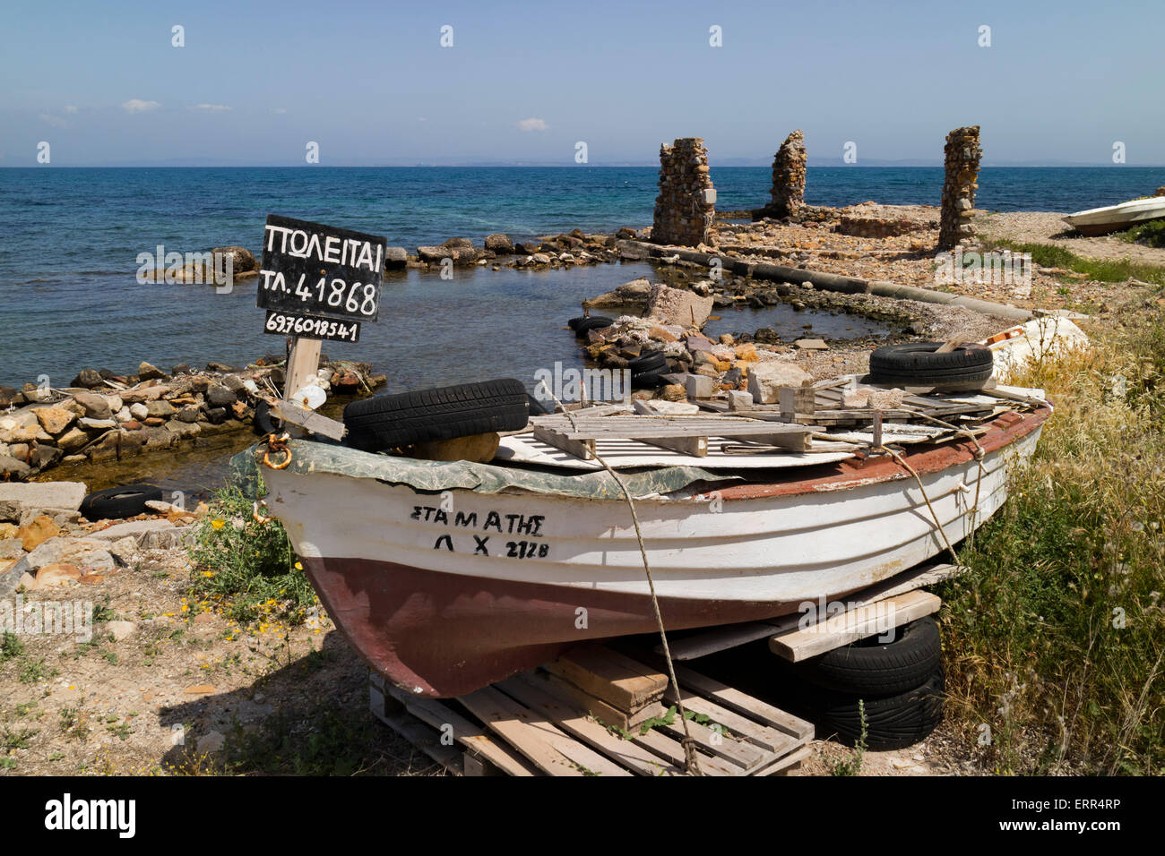 Little fishers boat on the Aegean Sea for sale on the isle of Chios, Greece with stone ruins in the background Stock Photo