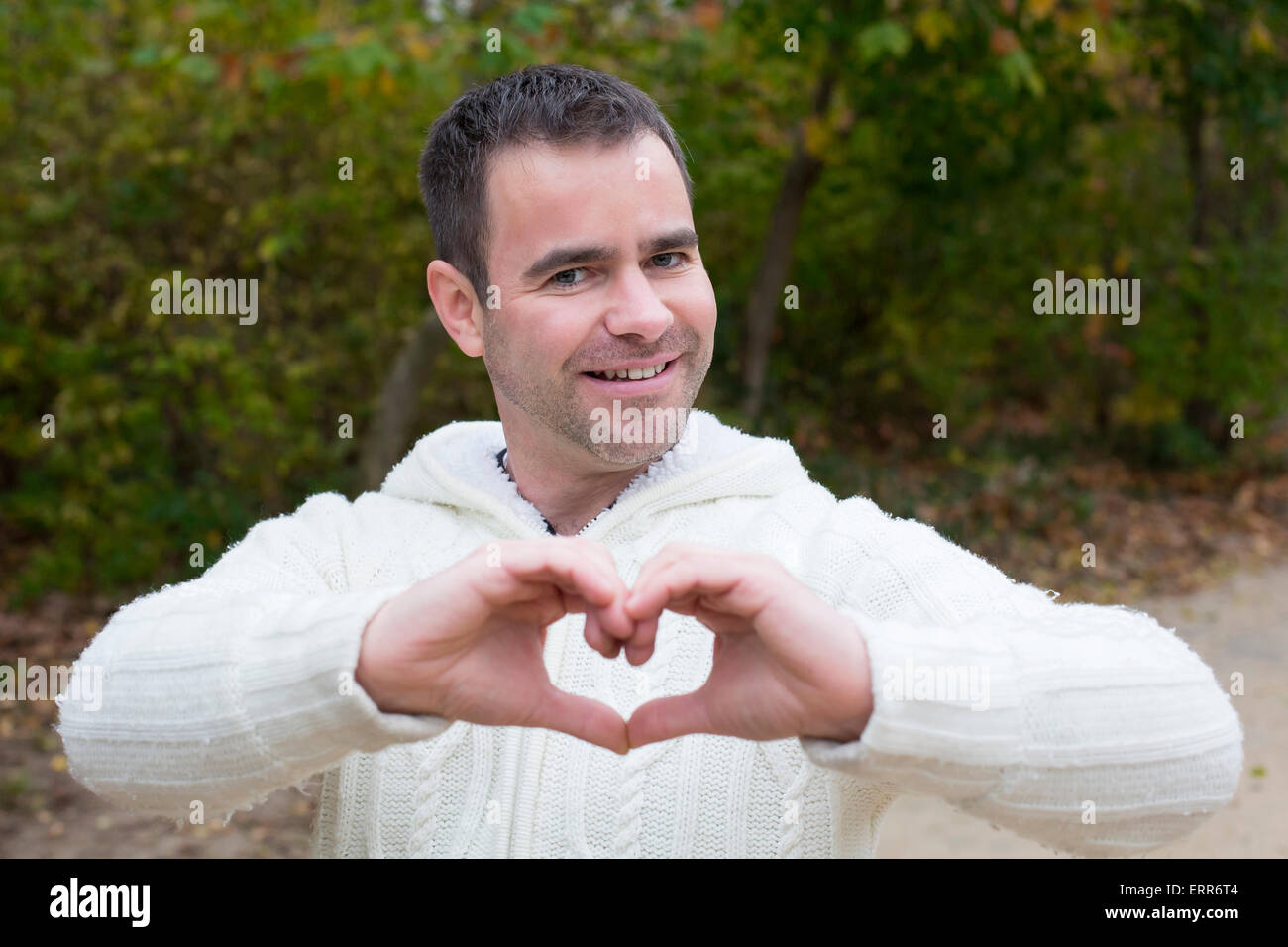 handsome man in a park shaping a heart with his hands Stock Photo