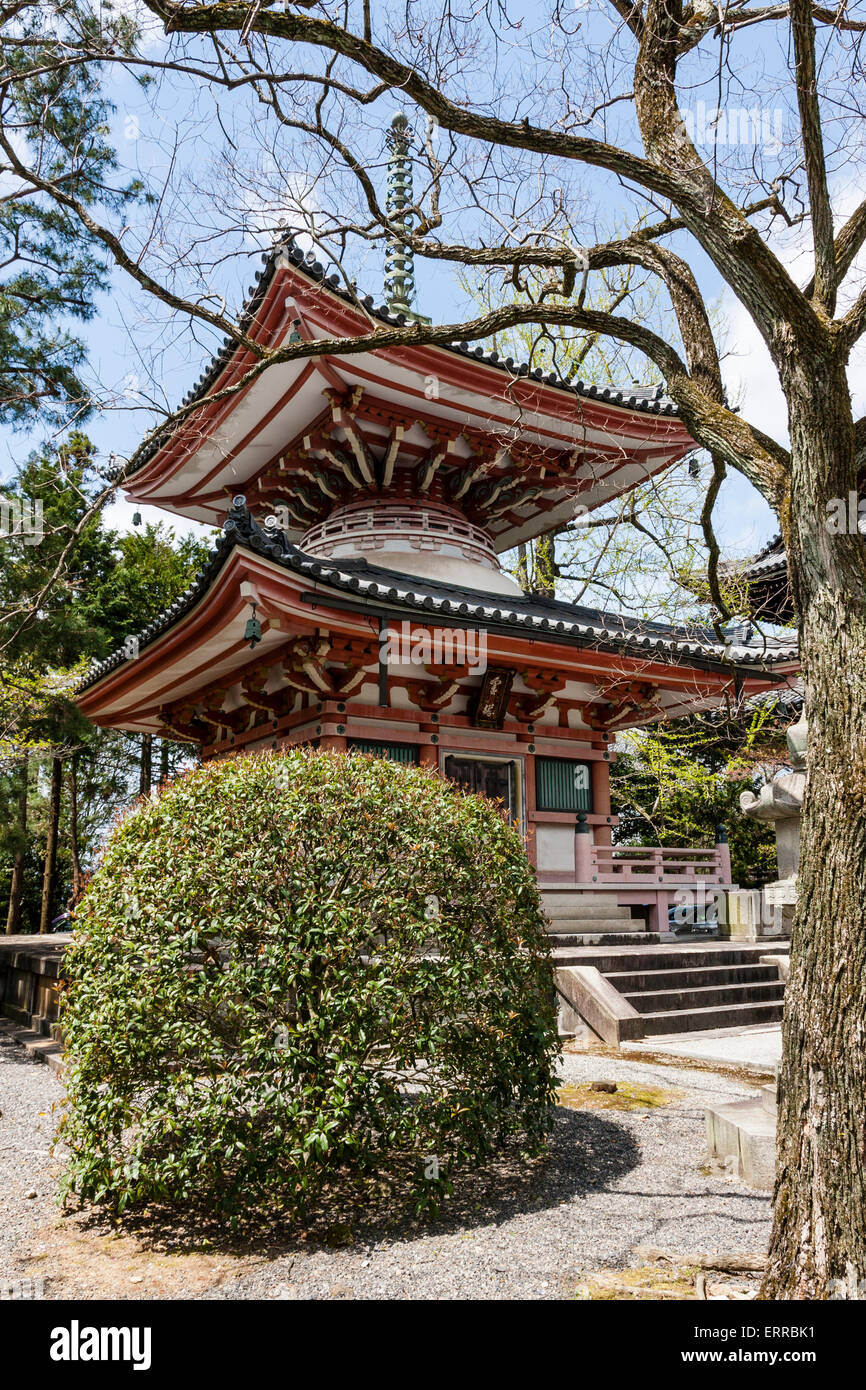 Japan, Kyoto, Chion-in Buddhist temple. Two story vermilion pagoda with trees and bushes around in the springtime. Cloudy blue sky background. Stock Photo