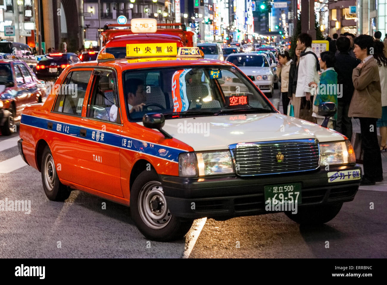 Japan, Tokyo, Ginza. Red and white taxi cab turning at night time Stock